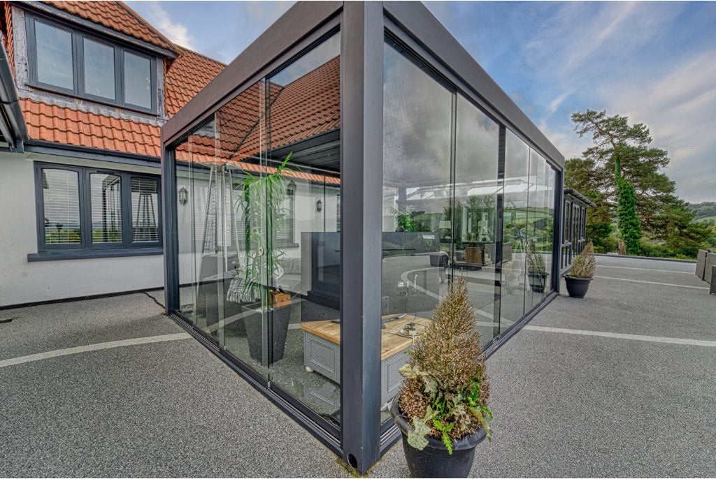Frameless glass sliding door system installed across the front of a louvred pergola