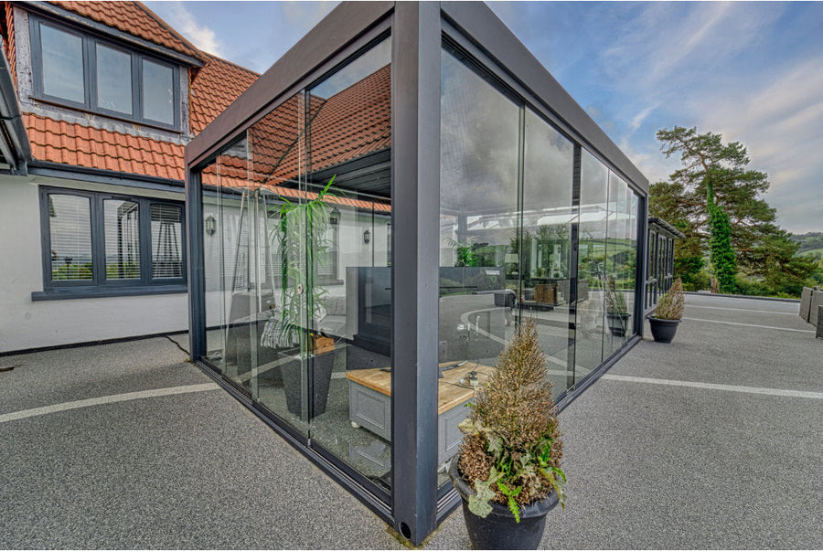 Frameless glass sliding door system installed across the front of a louvred pergola