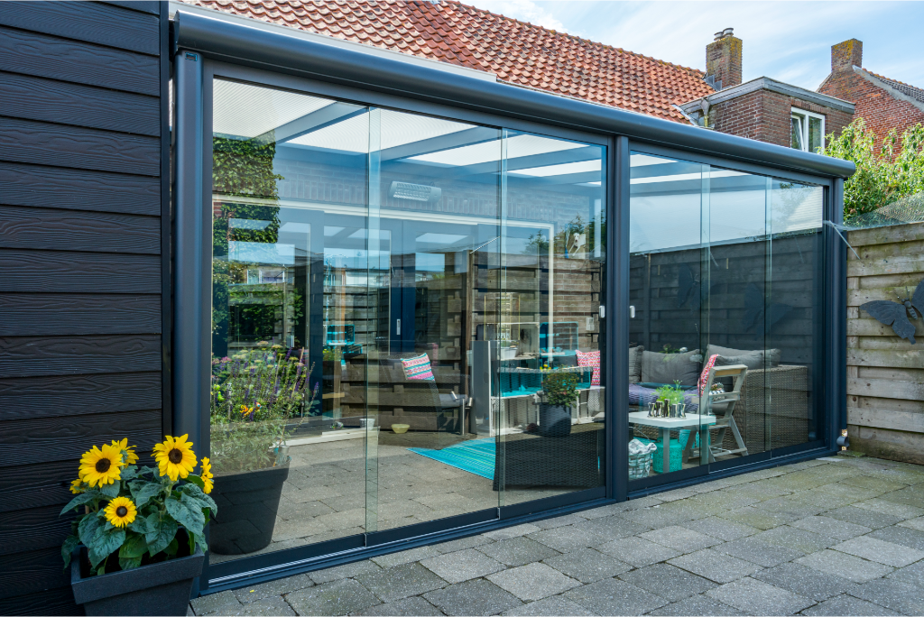 Roma Primo glass sliding door system on a wide veranda, panels partially open