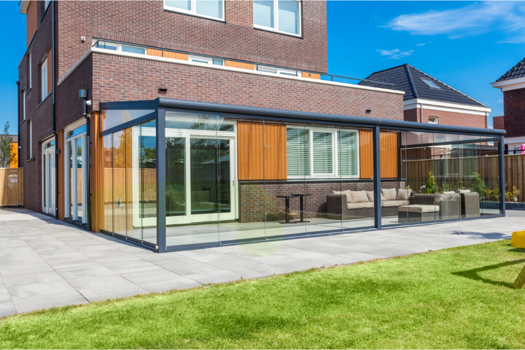 Frameless glass sliding doors on a modular veranda, panels stacked to one side