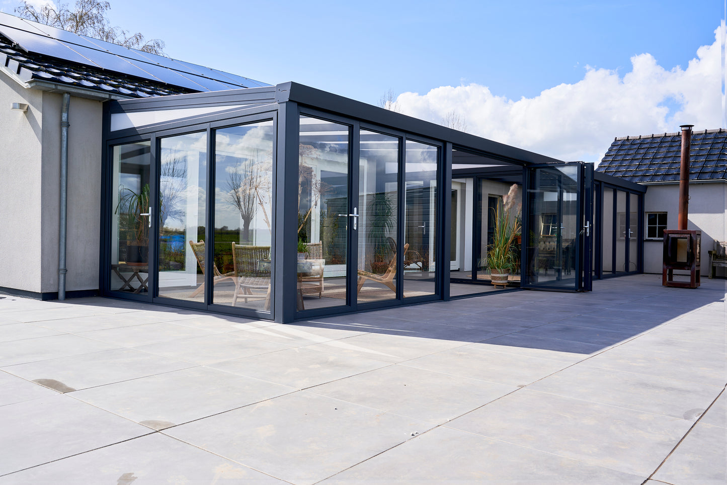 Slide and turn glass door in anthracite on a veranda, panels partially folded open