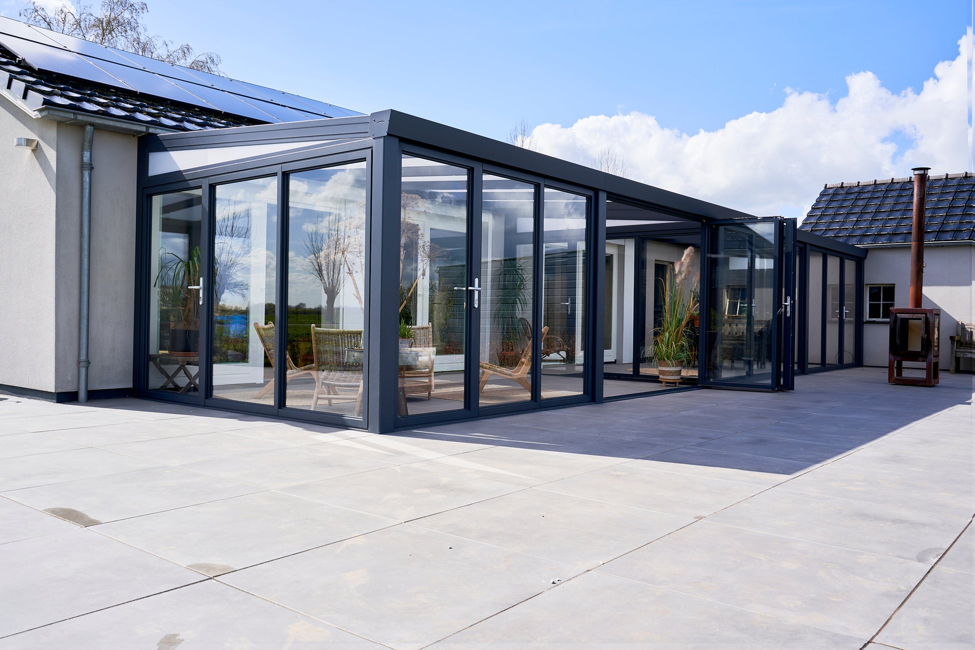 Slide and turn glass door in anthracite on a veranda, panels partially folded open
