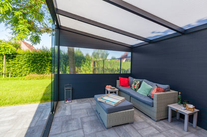 The Cascina veranda in anthracite positioned to shelter a garden dining table