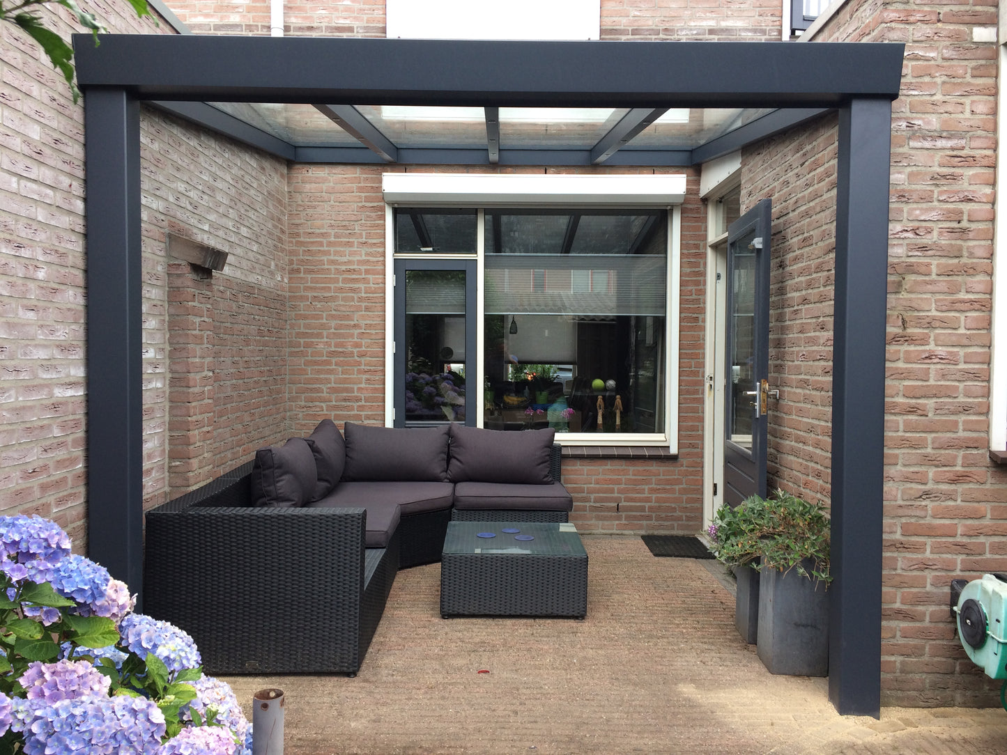 The Luxa veranda in anthracite spanning a wide terrace, oblique angle