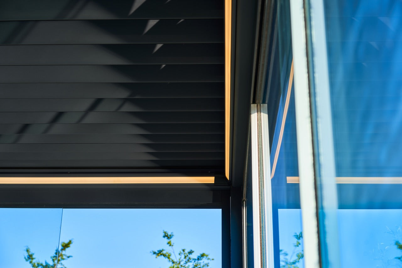 Aperto pergola in anthracite covering a garden terrace with outdoor lounge furniture below