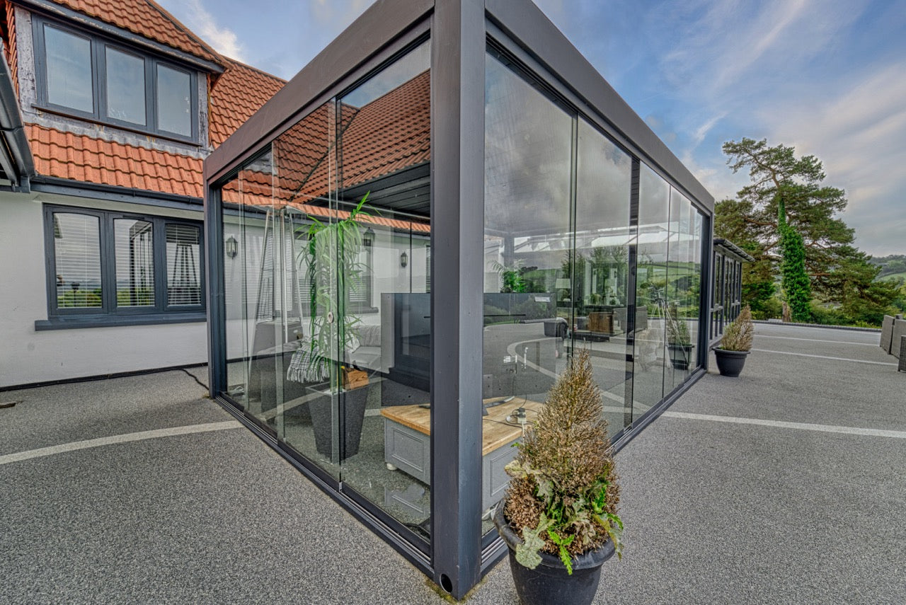 Aperto pergola in anthracite at dusk, LED-lit terrace below, panels closed