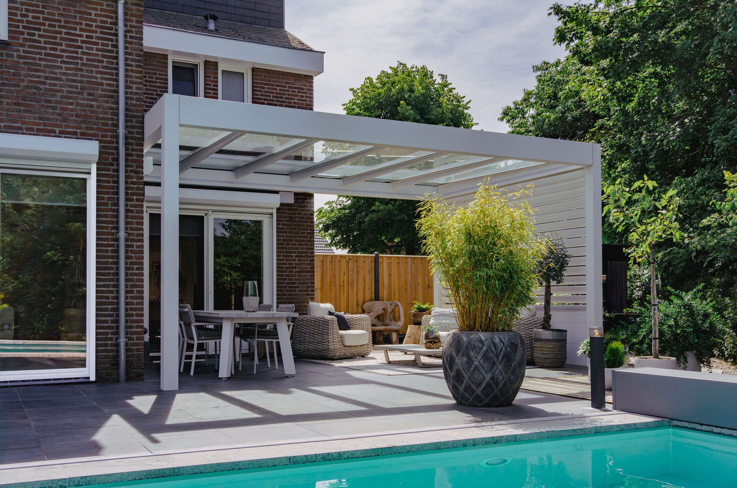 The Cristallo pergola in black spanning a rear garden terrace on a modern home