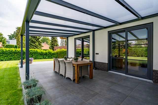 The Cascina veranda in anthracite on a brick home with arched windows behind